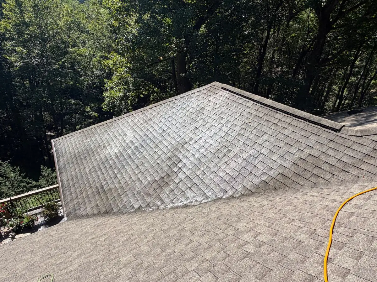 Asphalt shingle roof partway through soft washing in Blowing Rock