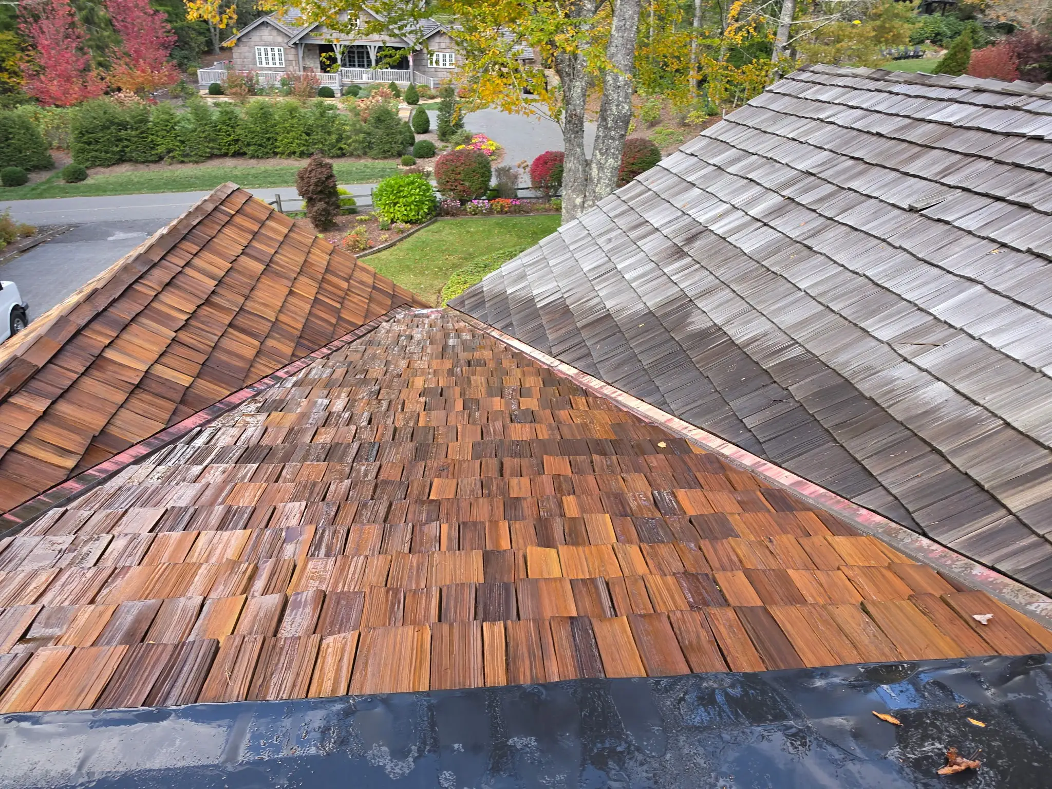 Cedar shake roof cleaned and oiled beside an untreated gray section in Linville