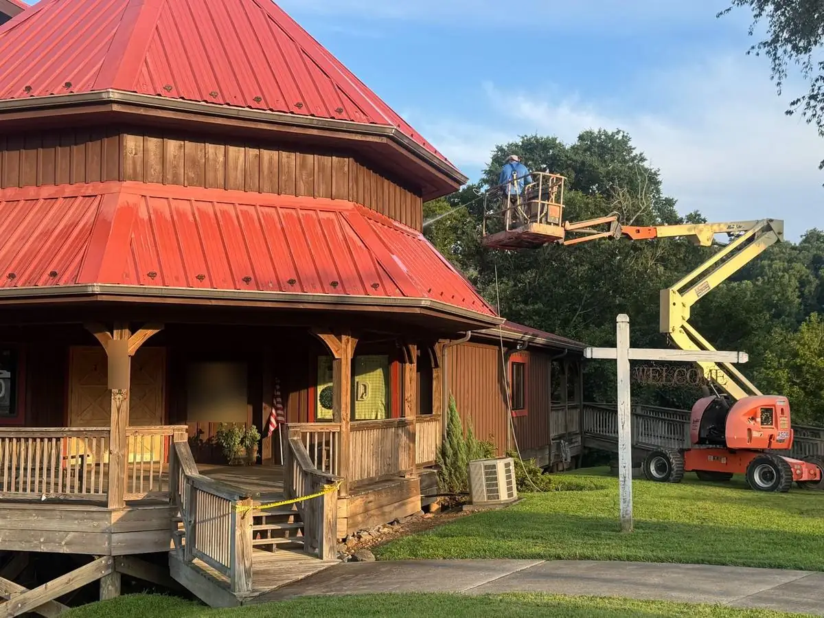 Boom lift washing a red metal roof