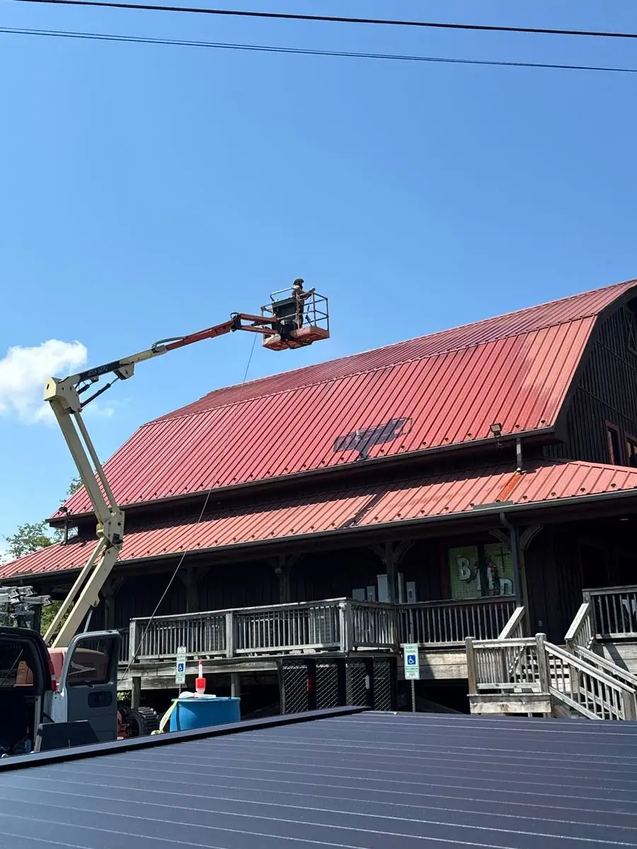 Technician in a lift cleaning a red metal roof